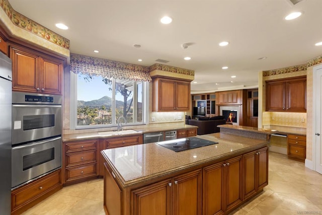 kitchen featuring a center island, sink, stainless steel appliances, light stone counters, and decorative backsplash