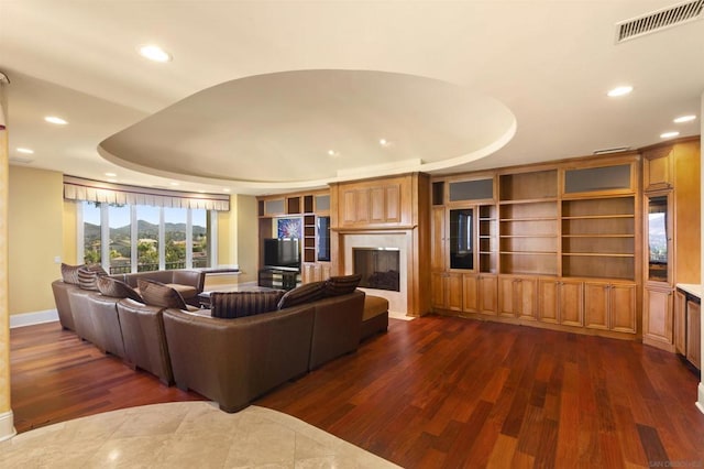 living room with dark hardwood / wood-style flooring and a tray ceiling