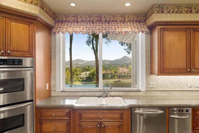 kitchen with a mountain view, decorative backsplash, sink, and double oven