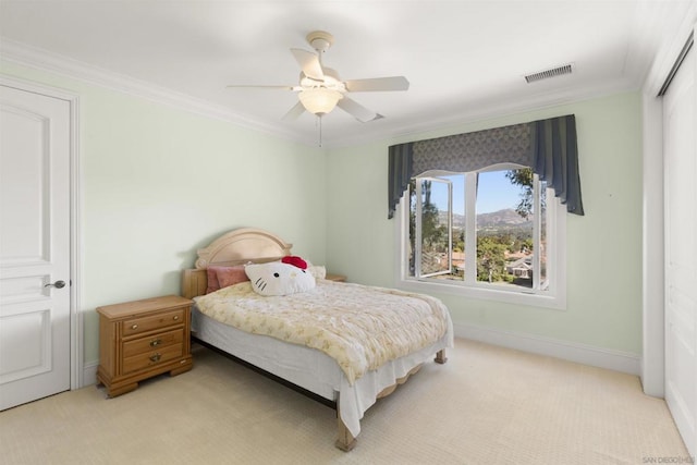 bedroom with ceiling fan, a closet, light carpet, and ornamental molding