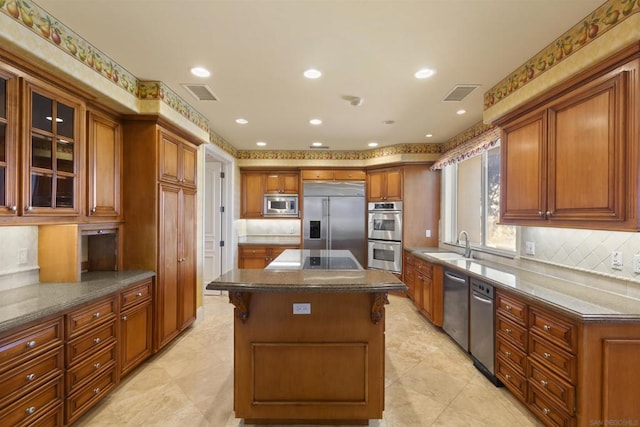 kitchen with a center island, a kitchen breakfast bar, built in appliances, dark stone countertops, and decorative backsplash