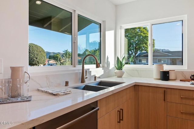 kitchen with dishwasher, sink, and light stone countertops