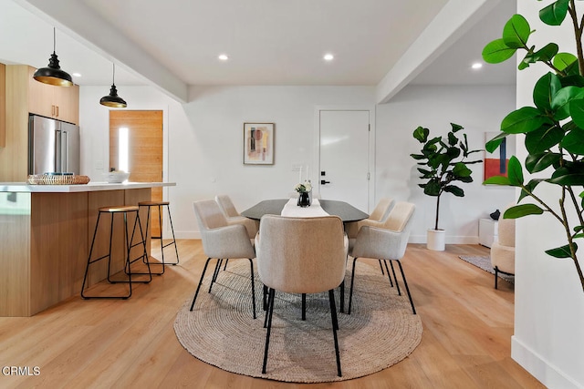 dining room featuring beamed ceiling and light hardwood / wood-style flooring