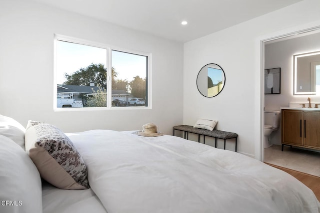 bedroom featuring light hardwood / wood-style floors, ensuite bath, and sink