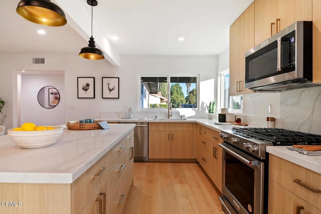 kitchen with sink, light brown cabinets, hanging light fixtures, stainless steel appliances, and light wood-type flooring