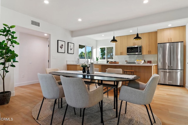 dining space with beamed ceiling and light wood-type flooring