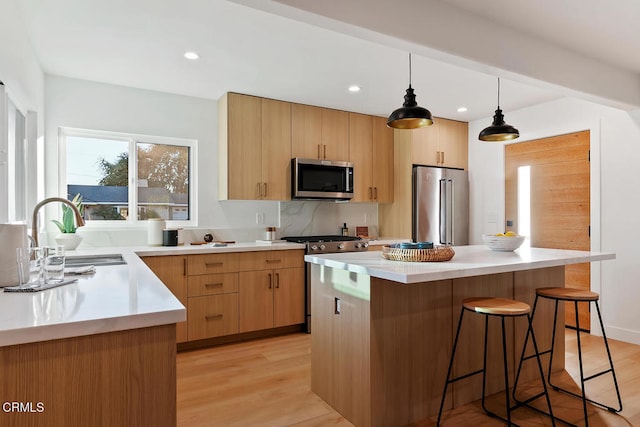 kitchen featuring sink, premium appliances, light hardwood / wood-style flooring, pendant lighting, and a kitchen island