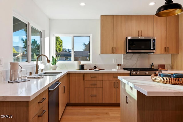 kitchen with backsplash, sink, stainless steel appliances, and light wood-type flooring