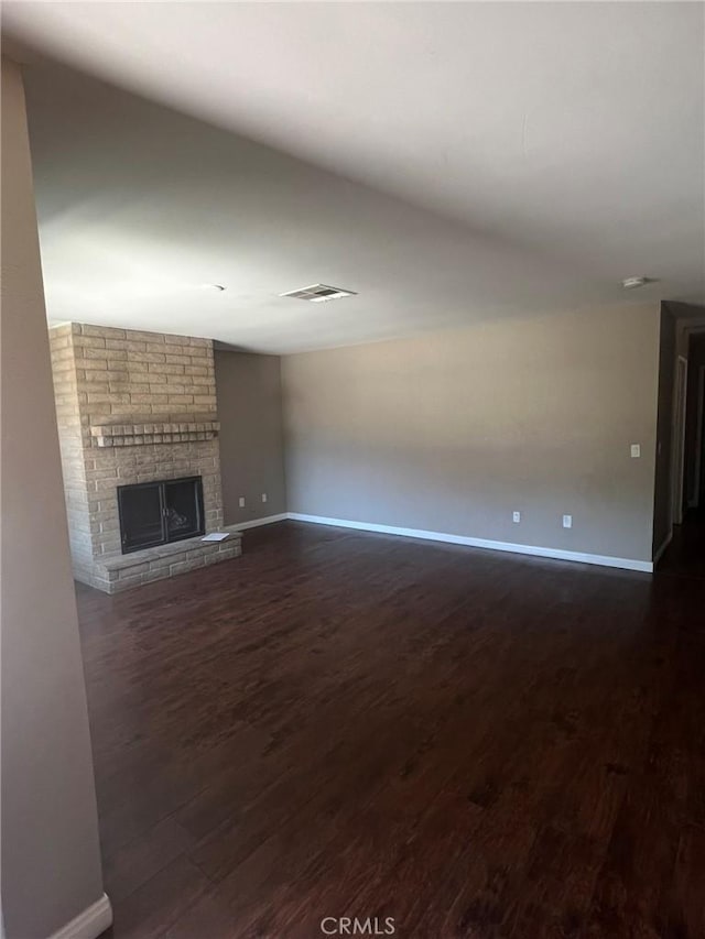 unfurnished living room with a large fireplace and dark hardwood / wood-style floors