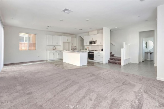 unfurnished living room featuring light carpet and sink