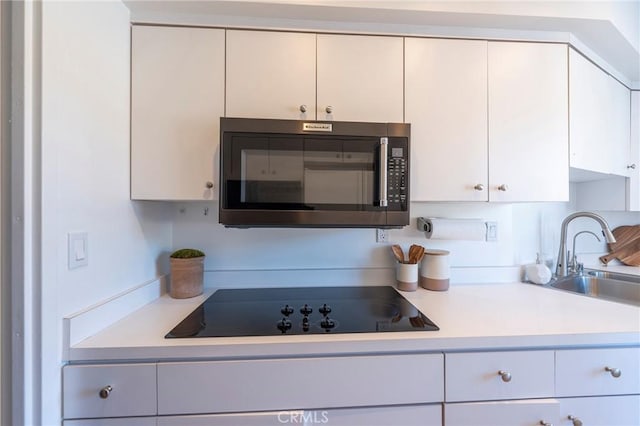 kitchen featuring sink, white cabinets, and black electric cooktop