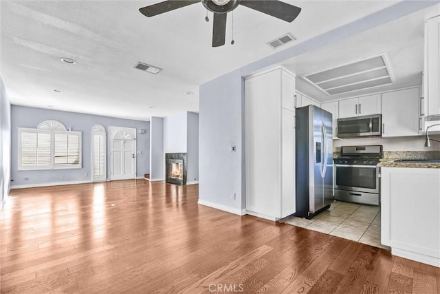 kitchen with white cabinetry, light wood-type flooring, light stone counters, and appliances with stainless steel finishes