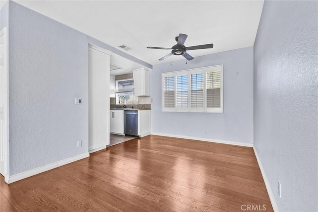 unfurnished living room with hardwood / wood-style floors, ceiling fan, and sink