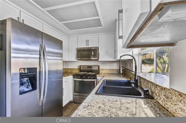 kitchen with appliances with stainless steel finishes, light tile patterned floors, white cabinetry, and sink