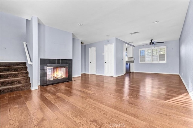 unfurnished living room featuring hardwood / wood-style floors, ceiling fan, and a fireplace