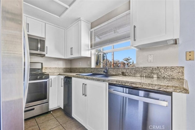 kitchen with tile patterned floors, sink, white cabinets, and appliances with stainless steel finishes