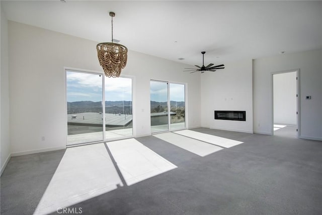 unfurnished living room featuring a mountain view and ceiling fan with notable chandelier