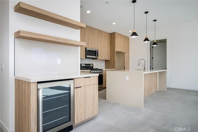 kitchen featuring appliances with stainless steel finishes, a kitchen island with sink, light brown cabinets, decorative light fixtures, and wine cooler