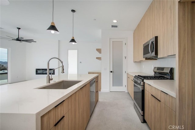 kitchen featuring stainless steel appliances, ceiling fan, sink, a large island with sink, and pendant lighting