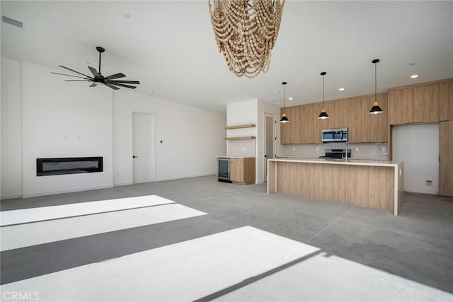 kitchen with appliances with stainless steel finishes, a kitchen island with sink, ceiling fan, decorative light fixtures, and wine cooler