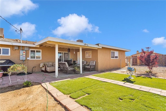 rear view of house featuring a lawn, an outdoor living space, and a patio