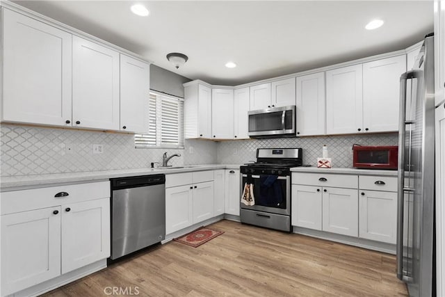 kitchen featuring white cabinetry, sink, stainless steel appliances, and light hardwood / wood-style floors