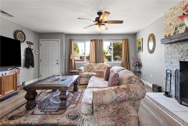 living room with ceiling fan, a fireplace, and light hardwood / wood-style floors