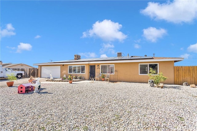ranch-style home featuring solar panels and a garage