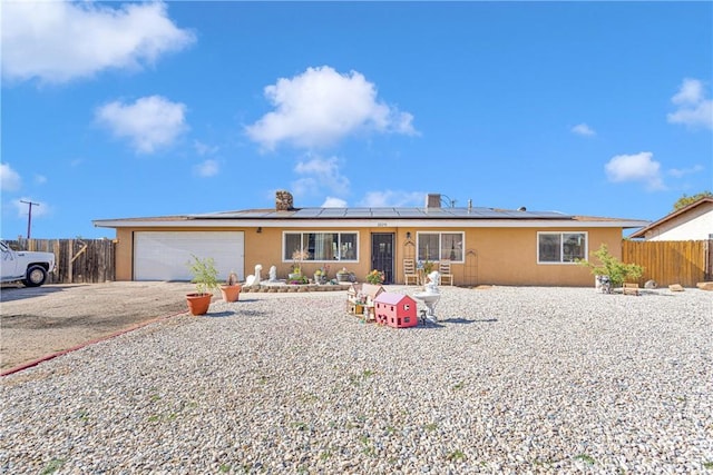 ranch-style home featuring a garage and solar panels