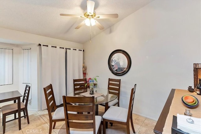 dining area with lofted ceiling, ceiling fan, light tile patterned floors, and a textured ceiling