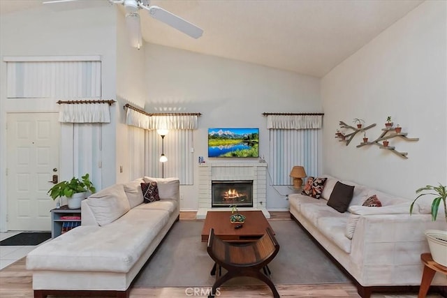 living room with ceiling fan, a fireplace, high vaulted ceiling, and wood-type flooring