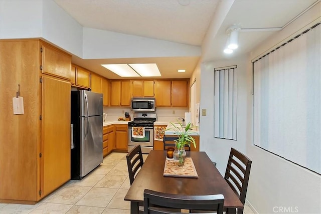 kitchen featuring light tile patterned flooring, appliances with stainless steel finishes, and vaulted ceiling