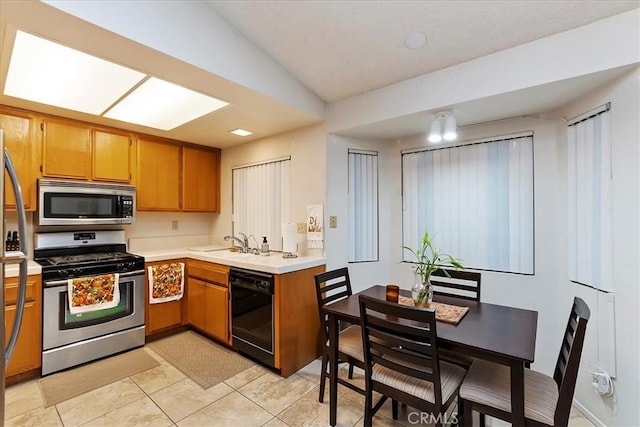 kitchen featuring light tile patterned floors, stainless steel appliances, lofted ceiling, and sink