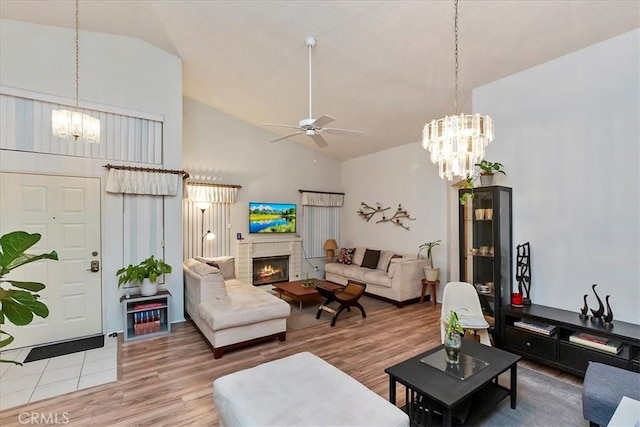 living room with ceiling fan, a fireplace, high vaulted ceiling, and wood-type flooring