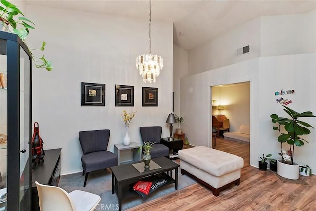 living room featuring a chandelier, wood-type flooring, and high vaulted ceiling