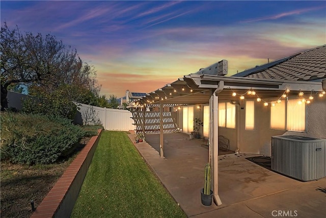 yard at dusk featuring central air condition unit and a patio area