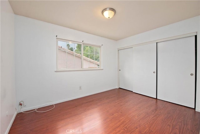 unfurnished bedroom featuring a closet and dark wood-type flooring