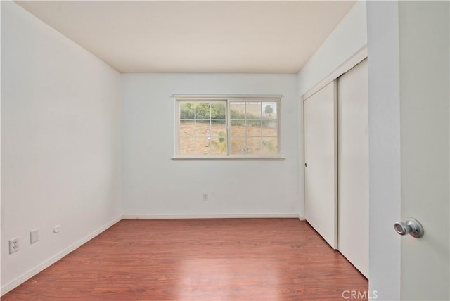 unfurnished bedroom featuring wood-type flooring and a closet