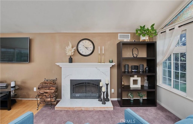 living room with a high end fireplace, lofted ceiling, and hardwood / wood-style flooring