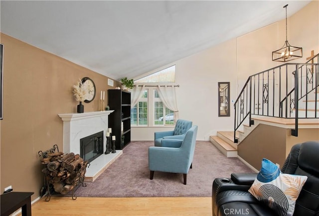 living room with a high end fireplace, hardwood / wood-style flooring, a chandelier, and lofted ceiling