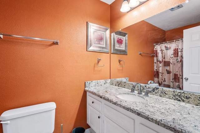 bathroom featuring vanity, toilet, and curtained shower