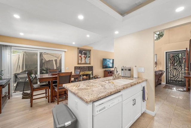 kitchen with dishwasher, sink, light stone countertops, light wood-type flooring, and white cabinetry