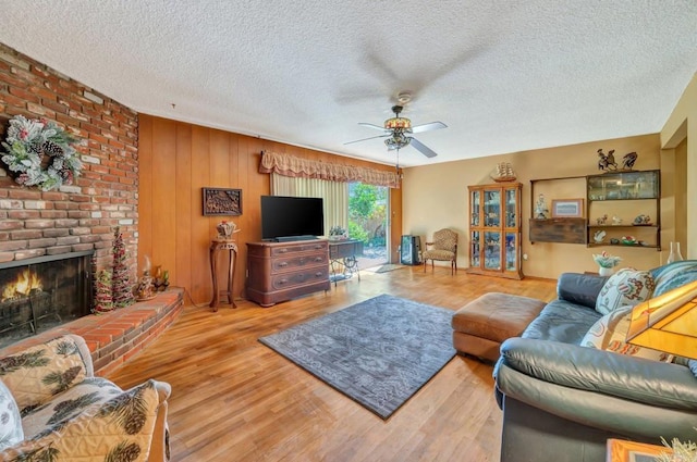 living room with wood-type flooring, a textured ceiling, ceiling fan, and a fireplace