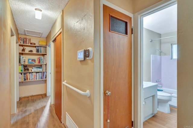 hall featuring light hardwood / wood-style floors and a textured ceiling