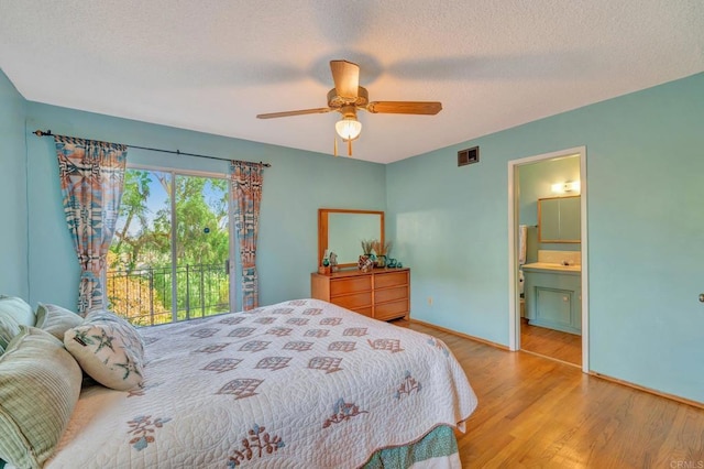 bedroom with ceiling fan, ensuite bathroom, a textured ceiling, and light wood-type flooring