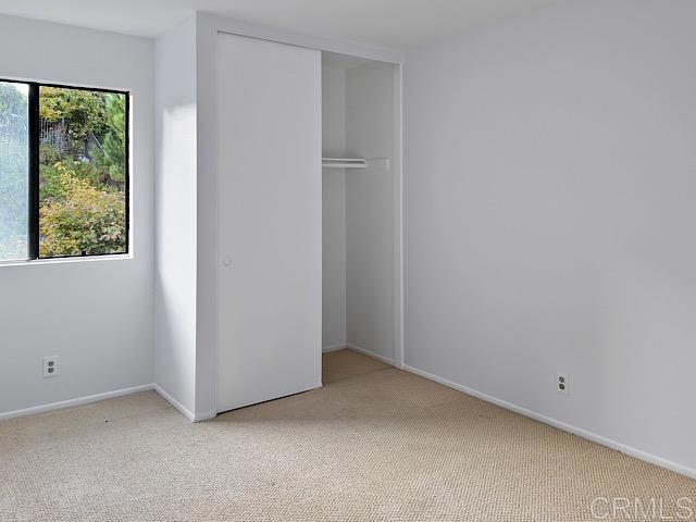 unfurnished bedroom featuring light carpet and a closet