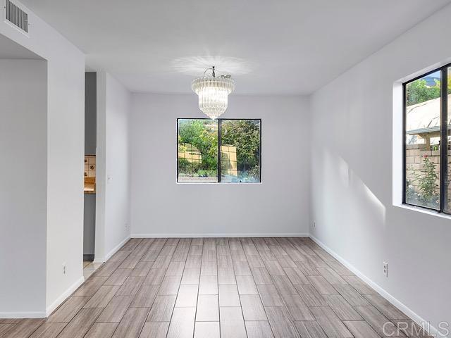 empty room with light hardwood / wood-style floors and a chandelier