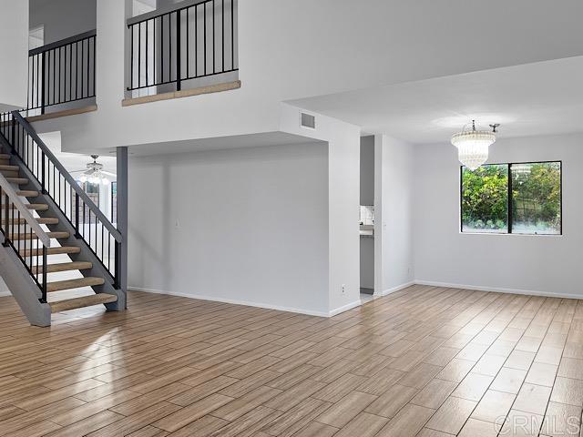 unfurnished living room featuring ceiling fan with notable chandelier and light hardwood / wood-style floors