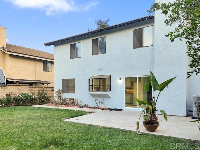 rear view of house with a patio and a lawn