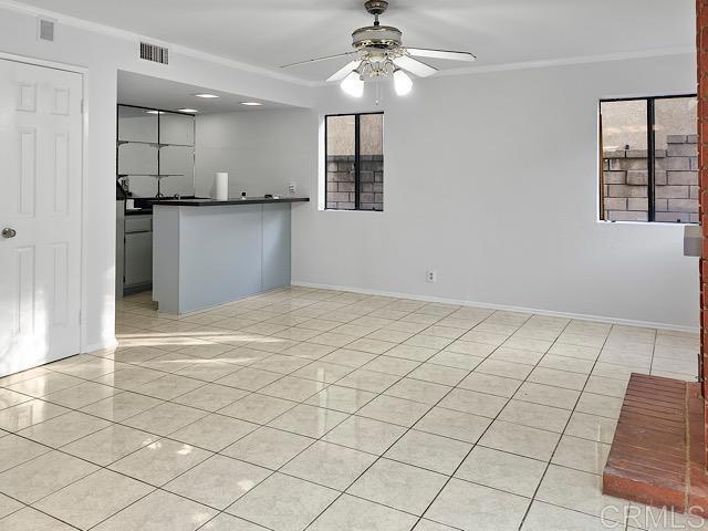 interior space featuring light tile patterned floors, ceiling fan, and crown molding